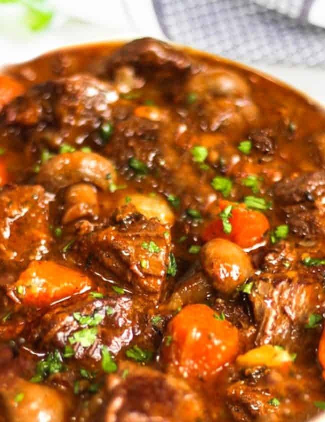 shot of beef stew with herbs in the background