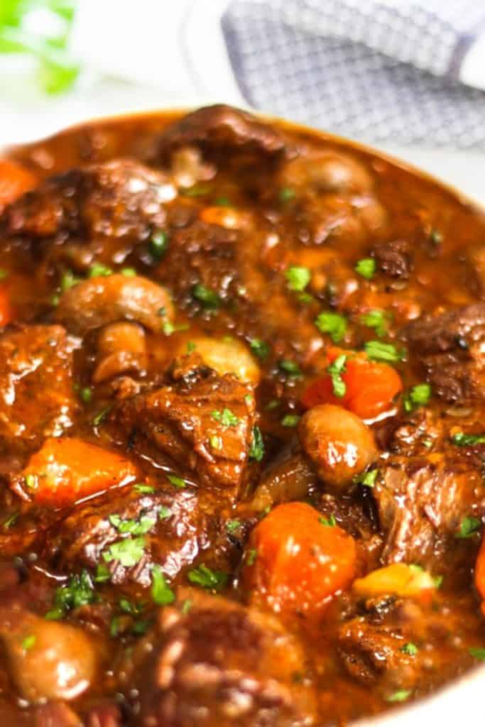 shot of beef stew with herbs in the background