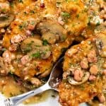Golden-brown Chicken Marsala cutlets topped with a creamy mushroom and bacon sauce, garnished with chopped parsley, served on a white plate with a spoon lifting one piece.