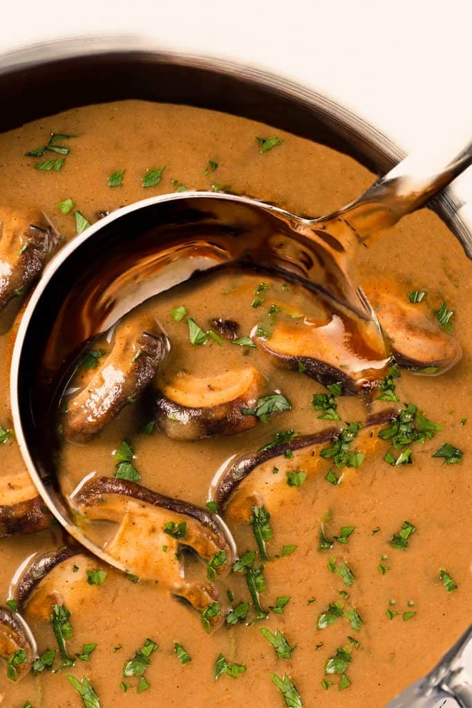 golden mushroom soup being ladled out of a pot