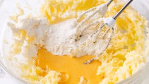 Flour being mixed into creamed butter and eggs with an electric mixer.