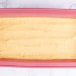 Smooth lemon pound cake batter evenly spread in a pink loaf pan, ready to be baked.