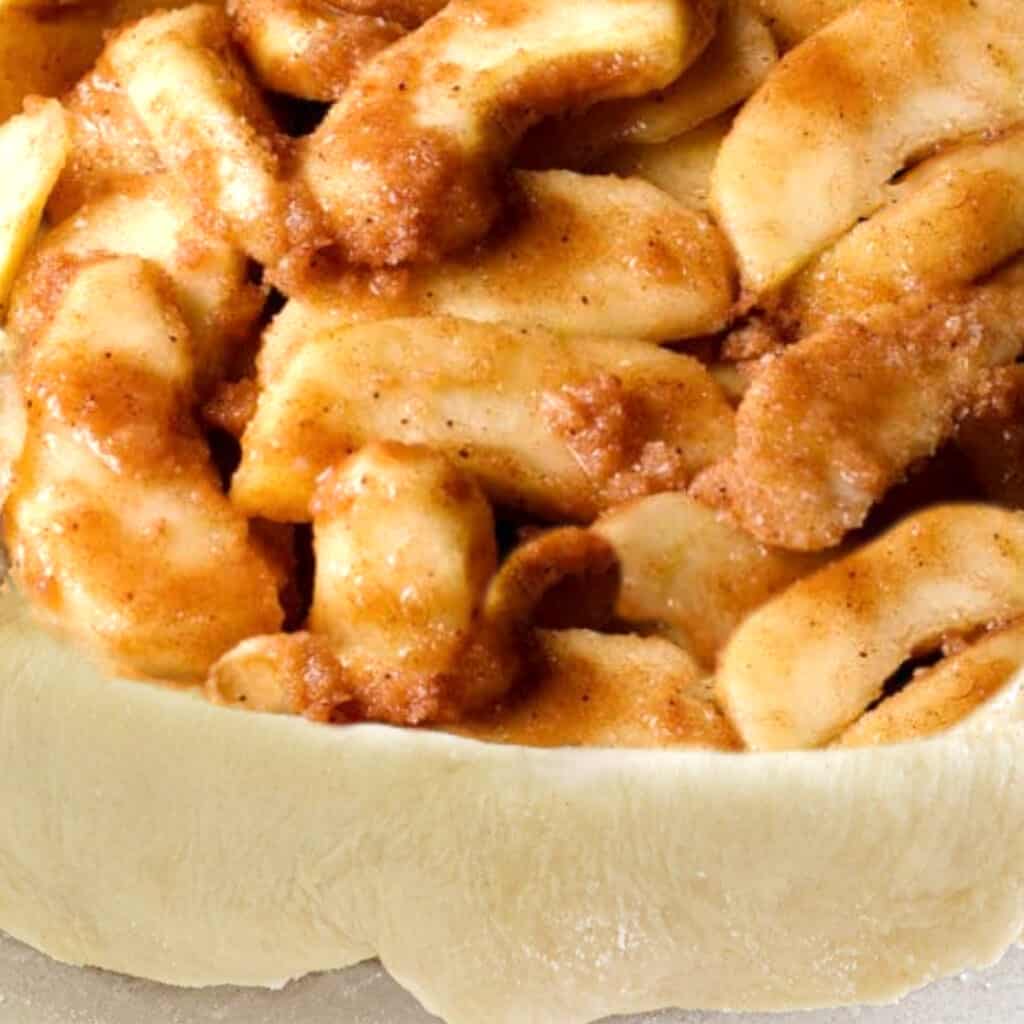 apple filling added to a pie dish with the dough