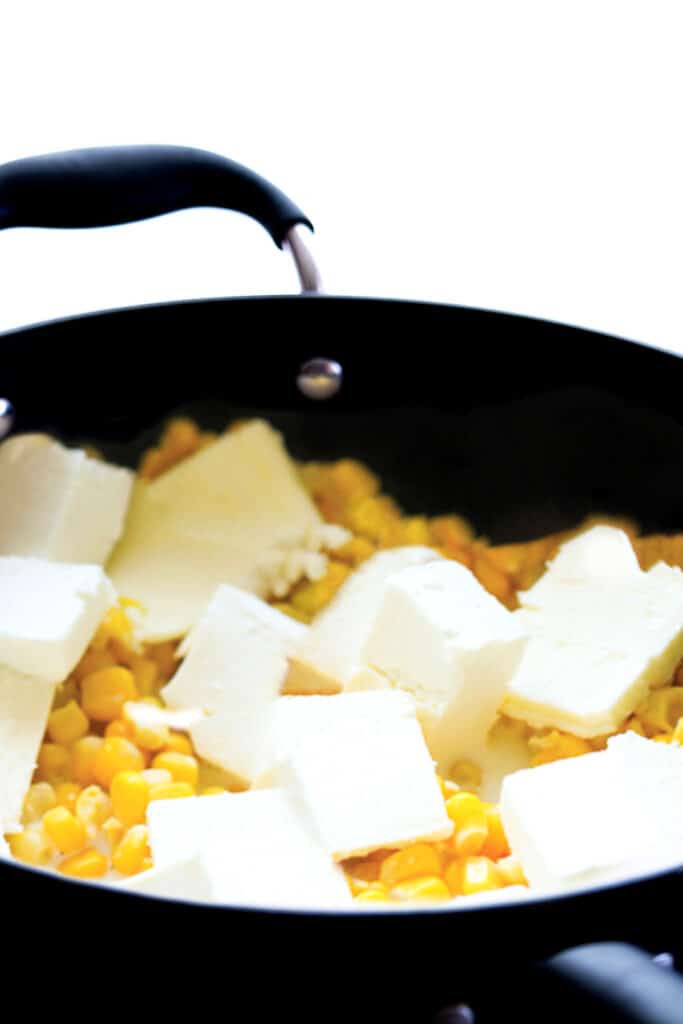 cubes of butter and cream cheese added to the pan with the corn mixture