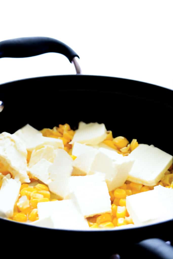 cubes of butter and cream cheese added to the pan with the corn mixture