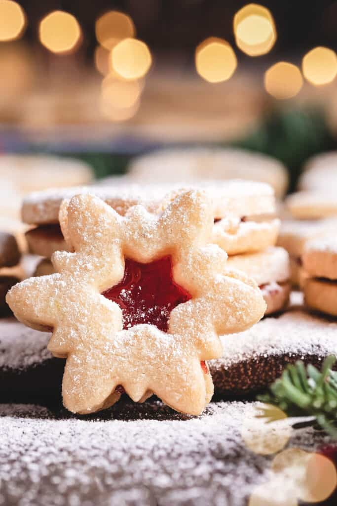 a snowflake shaped cookie filled with jam on a platter