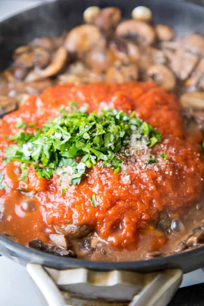 tomato sauce and herbs in pan with mushrooms