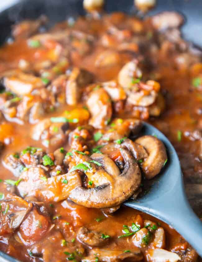 mushrooms in a tomato sauce in a pan with a spoon