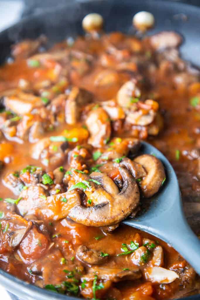 mushrooms in a tomato sauce in a pan with a spoon