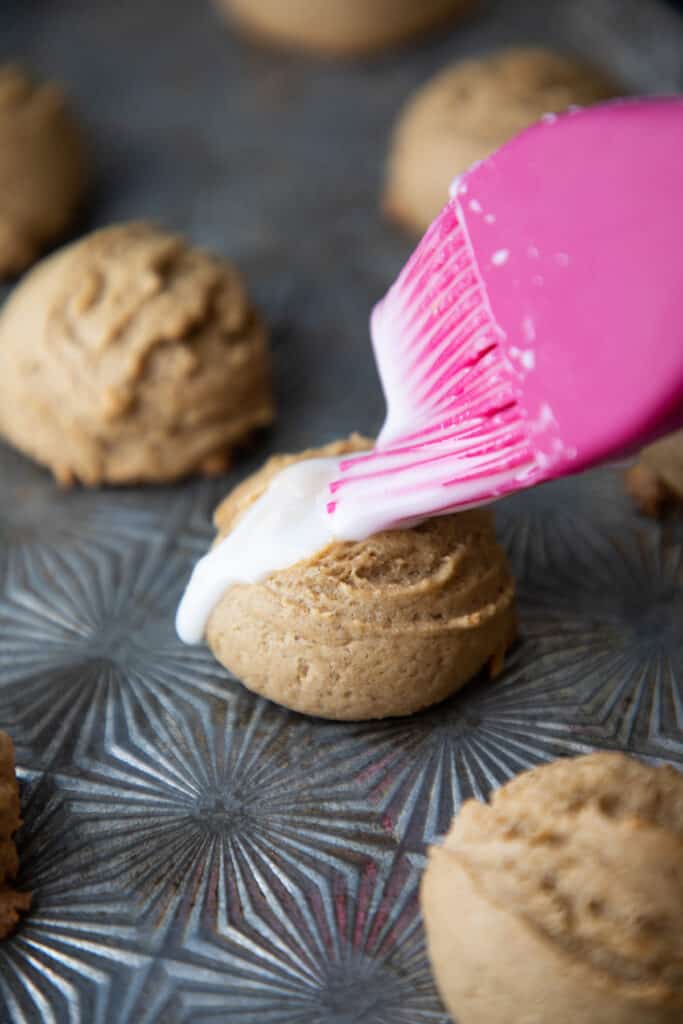 cookie dough mounds being brushed with sugar paste