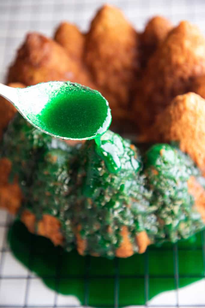 Christmas tree cake being drizzled with green icing