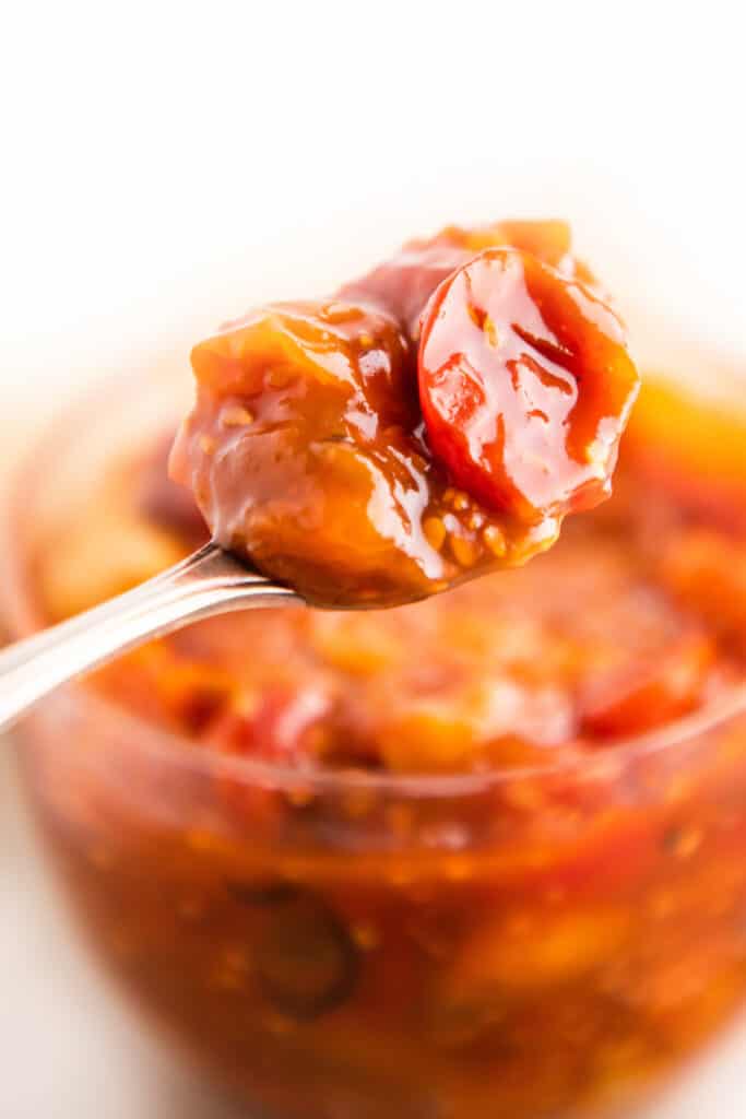 a jar of tomato jam with a spoonful