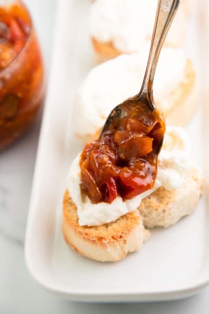 a spoonful of tomato jam ready to be spread on toasted bread with burrata