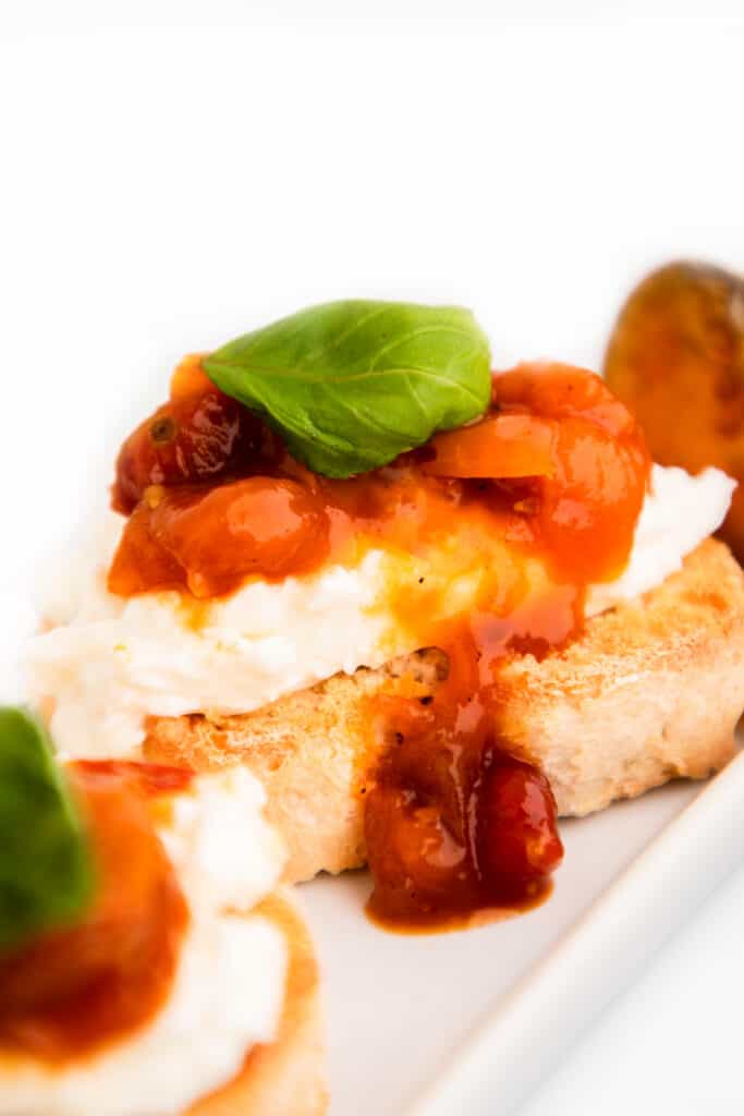 Crostini with burrata cheese, tomato jam and a basil garnish
