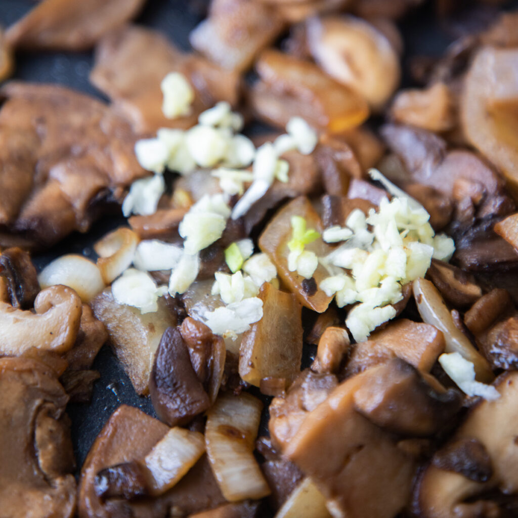 garlic added to the pan with the cooked mushrooms