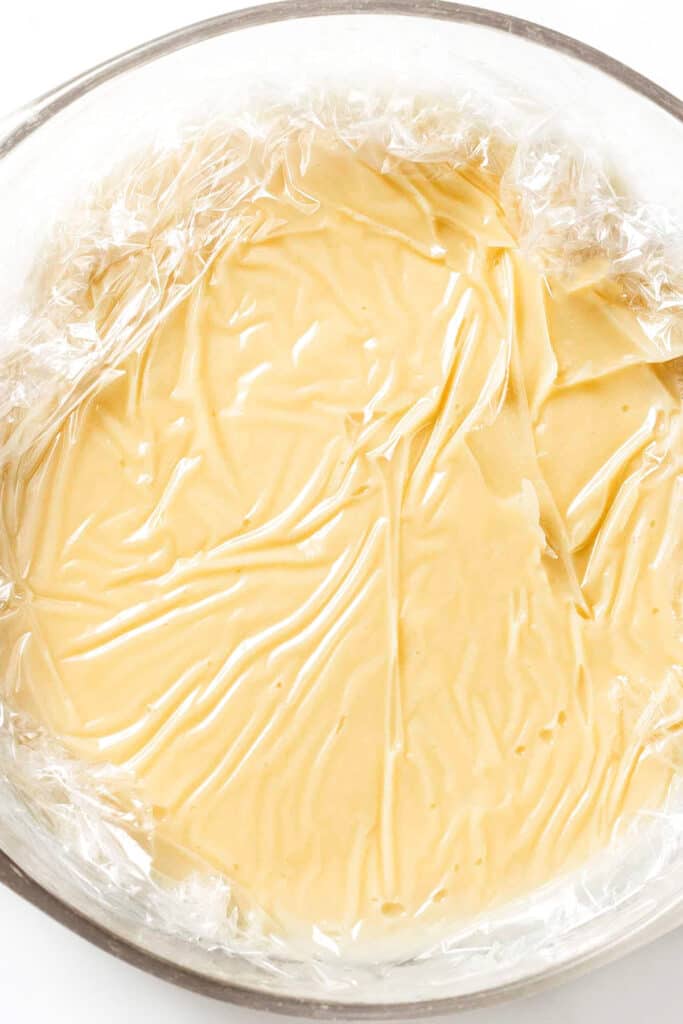 pastry cream in a glass bowl covered with plastic wrap