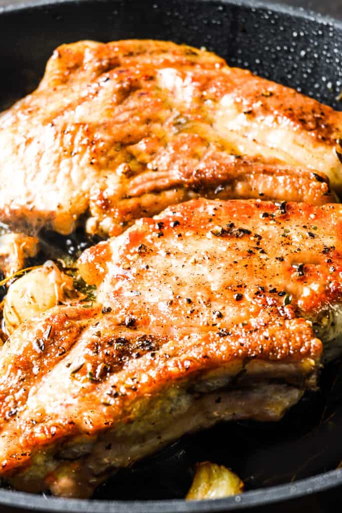 browned pork chops in a cast iron pan