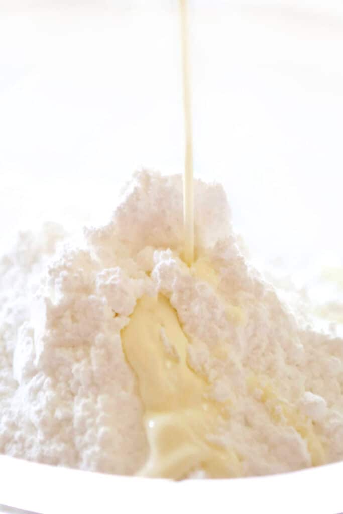 milk being poured onto powdered sugar