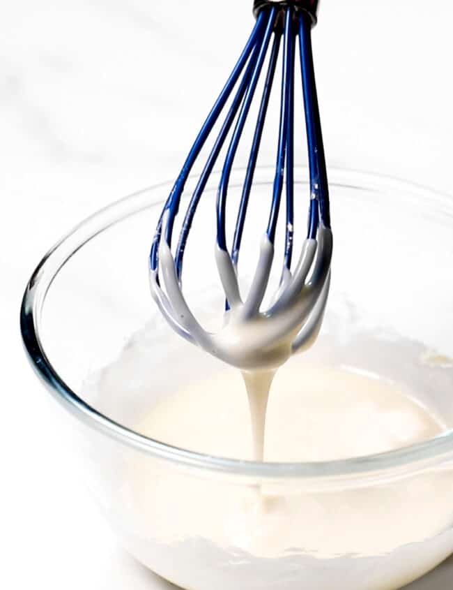 donut glaze dripping from a whisk into a bowl