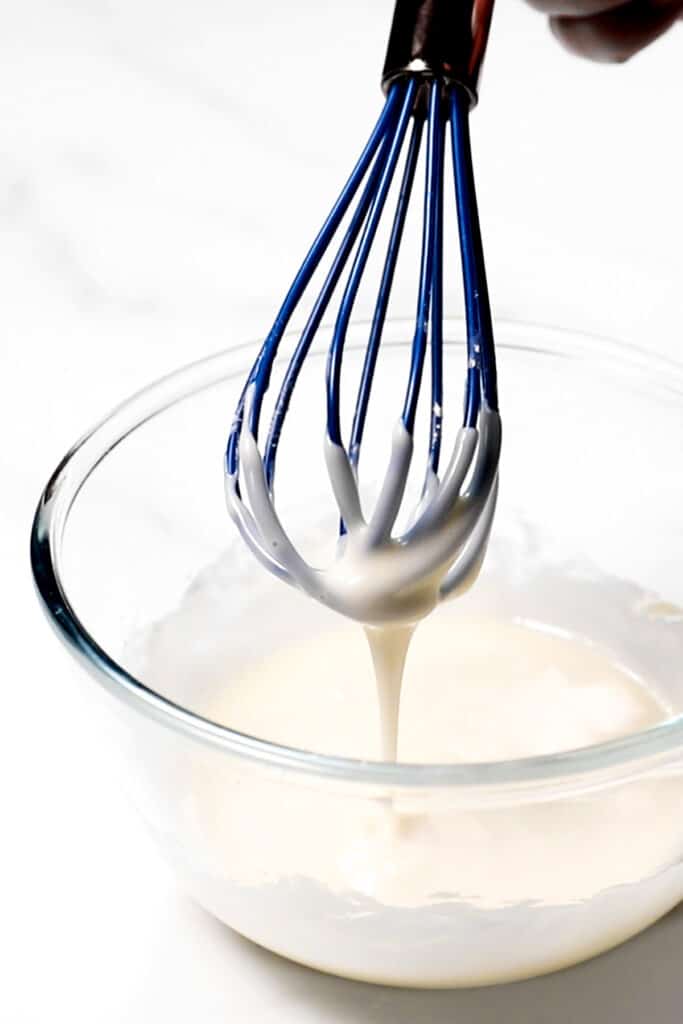 donut glaze dripping from a whisk into a bowl