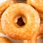 A close up of a pile of glazed cake donuts