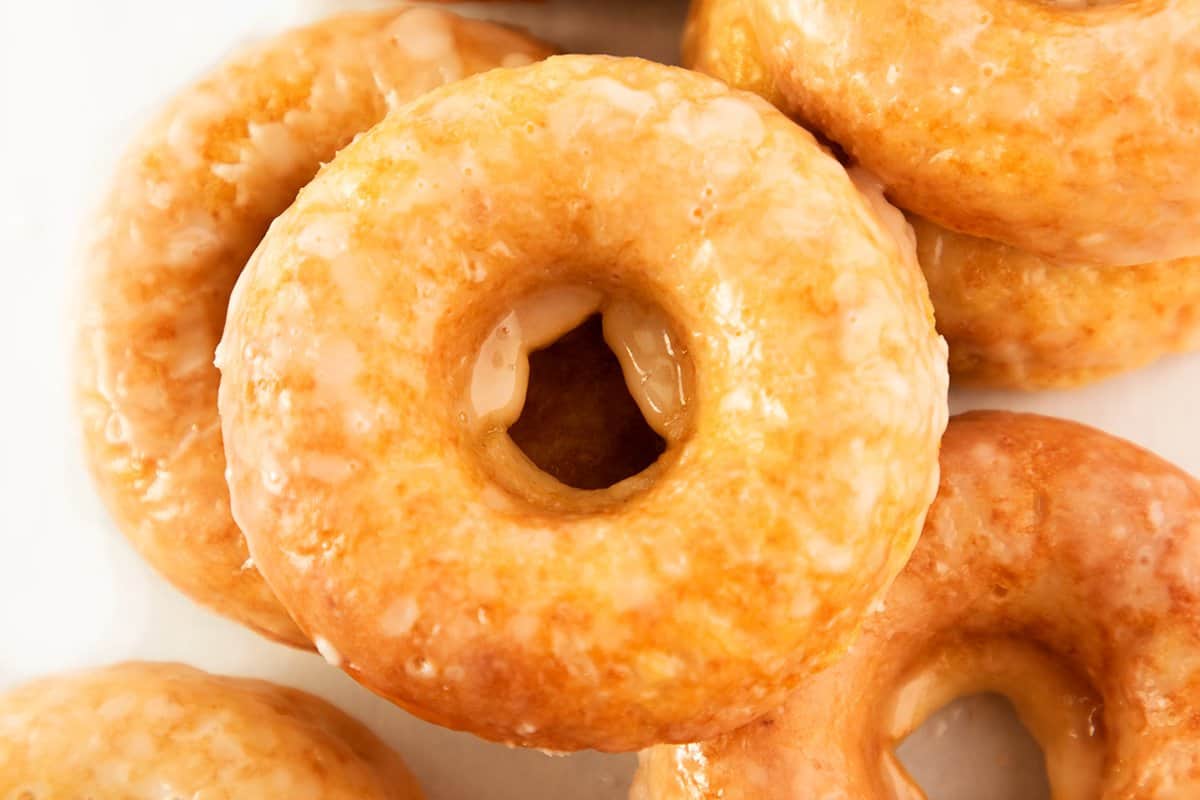 A close up of a pile of glazed cake donuts