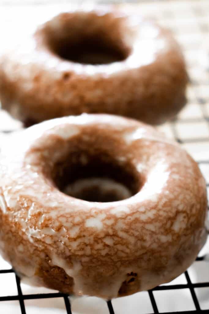 two glazed donuts on a cooling rack