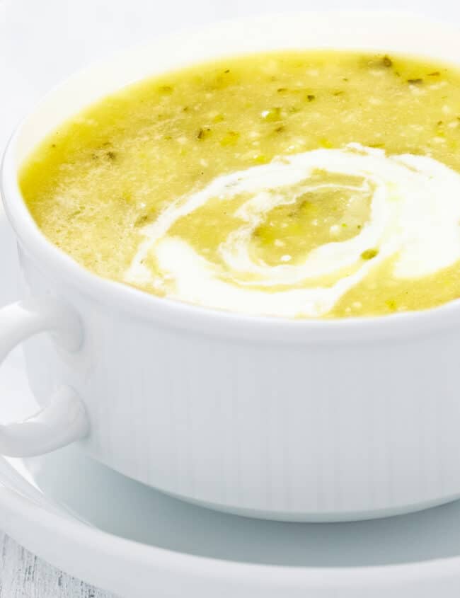 a close up of a bowl of zucchini soupswirled with sour cream