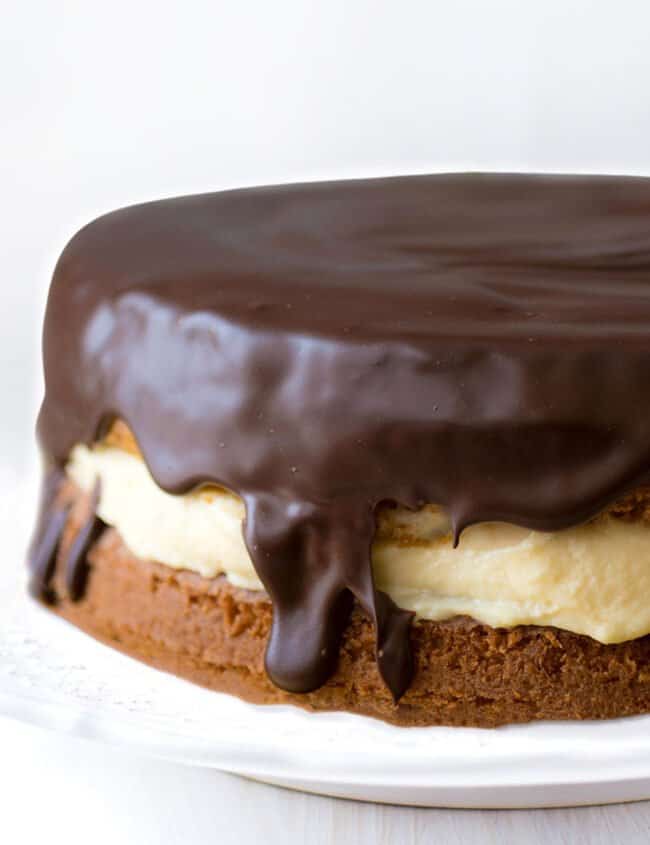 a close up of a vanilla cake filled with custard and covered in chocolate glaze