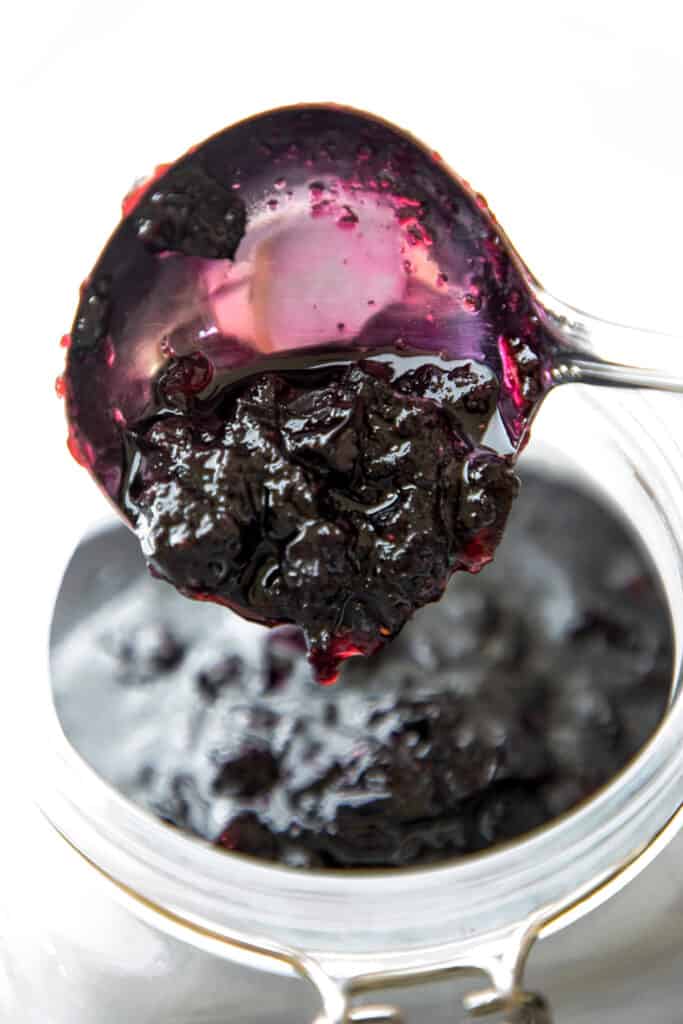 hot blueberry jam being spooned into a jar