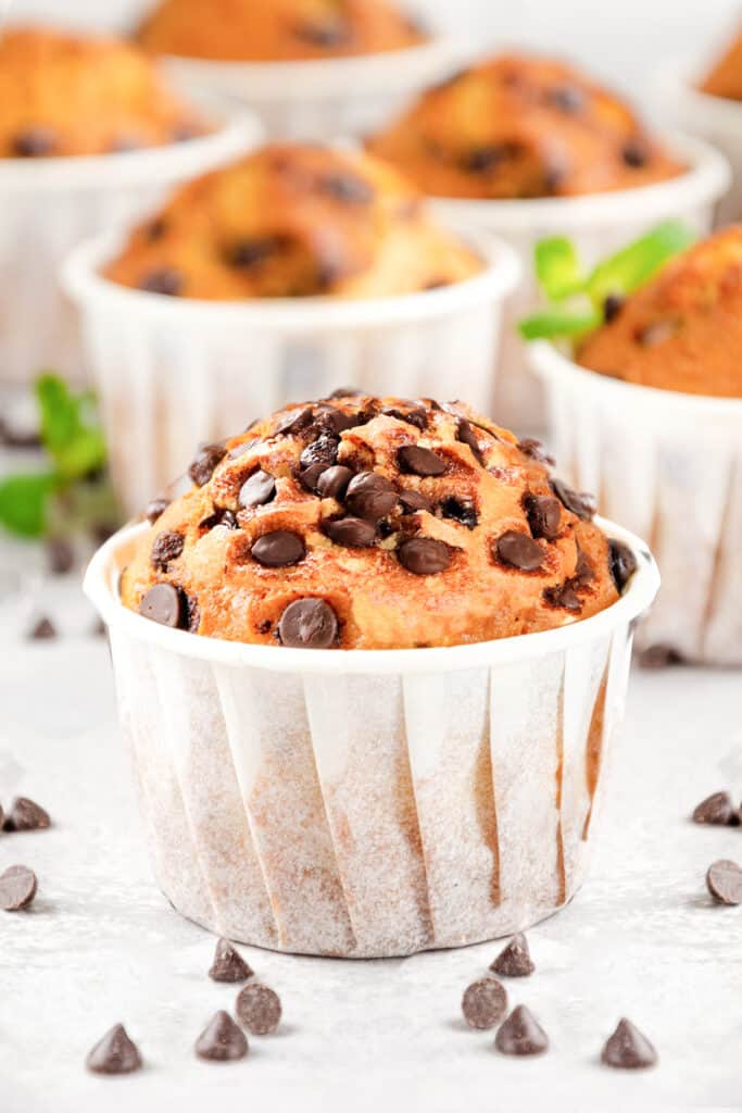 a group of Chocolate Chip Muffins with chocolate chios scattered on the table