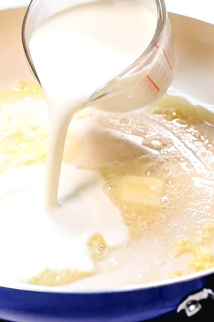 the cream pouring into the pan with the garlic