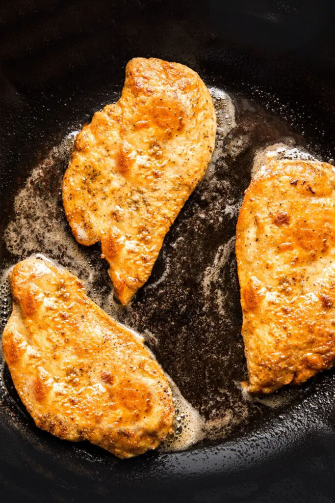 chicken breasts frying in a pan