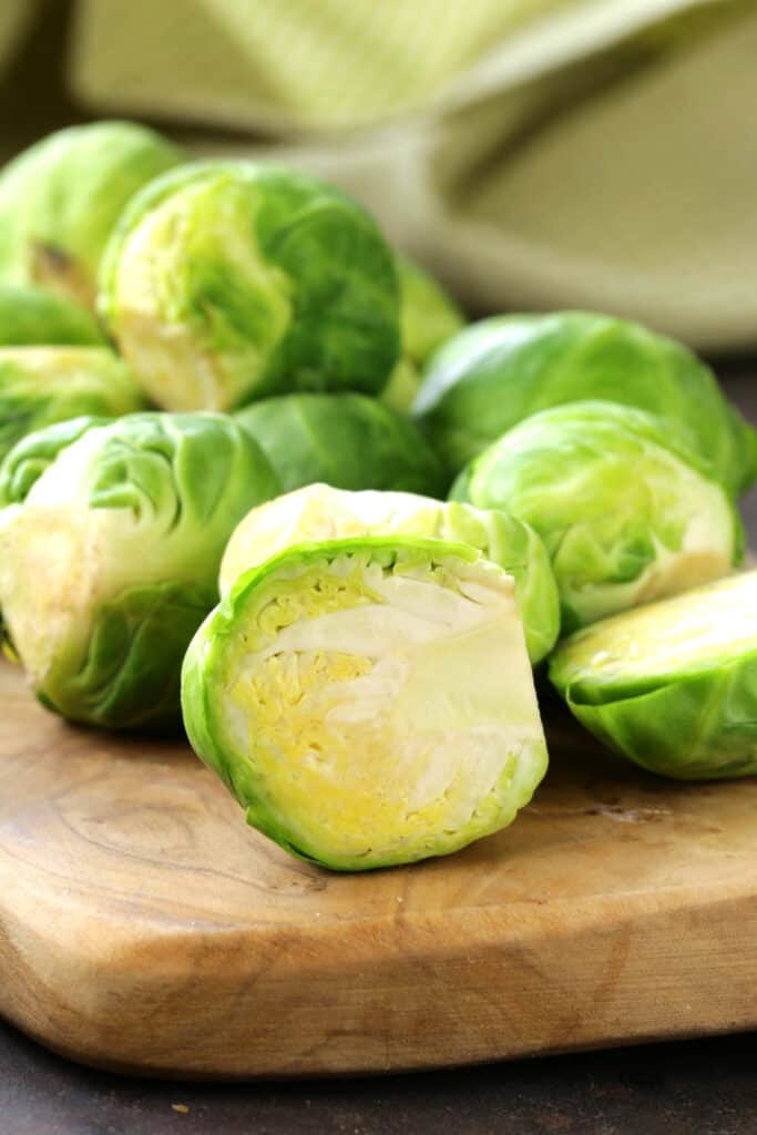 a cutting board with halved Brussels sprouts