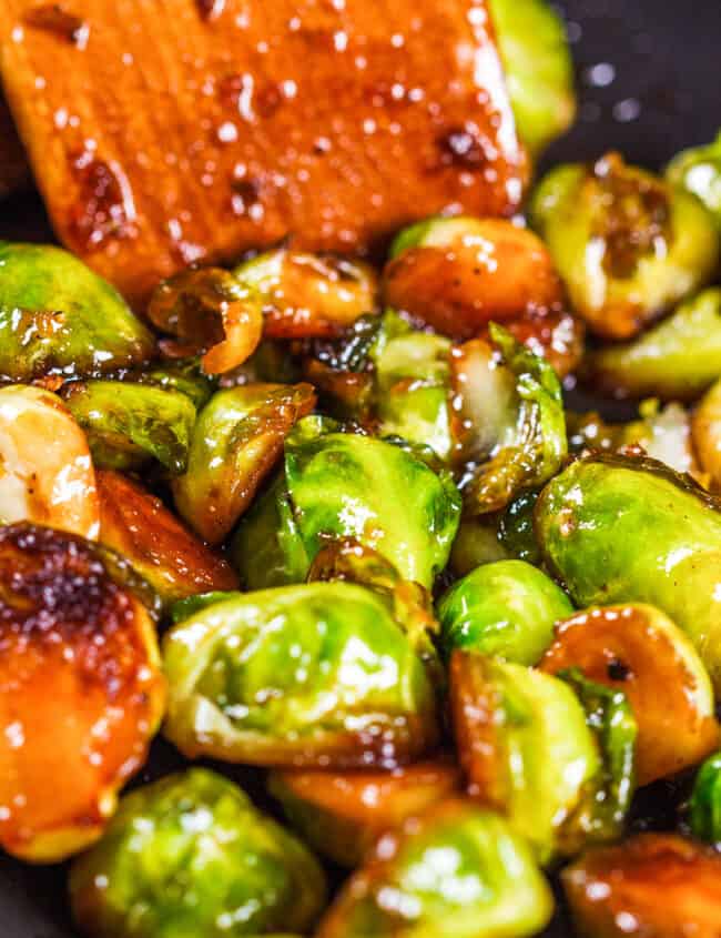 a close up image of Brussel sprouts in a pan covered in a brown sauce.