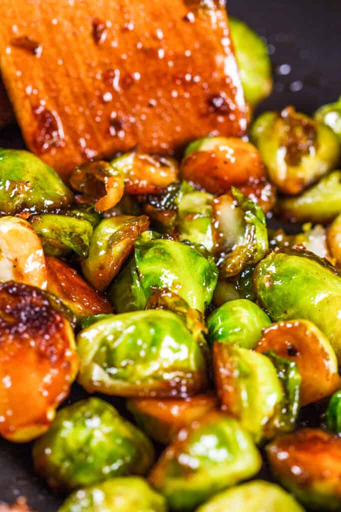 a close up image of Brussel sprouts in a pan covered in a brown sauce.