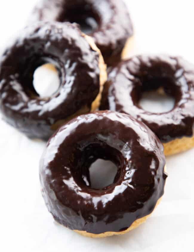 Four Chocolate frosted donuts with a white backgroound