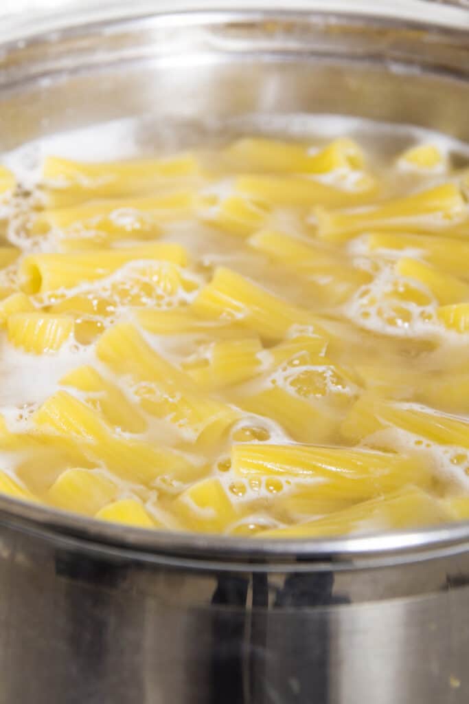a close up image of pasta cooking in boiling water.