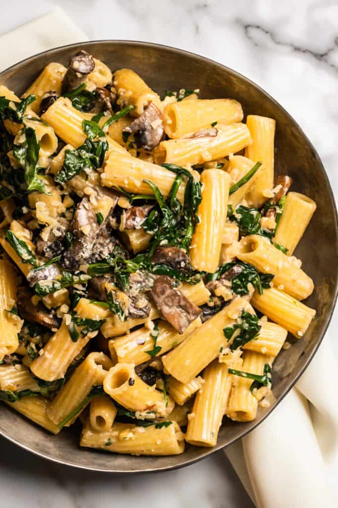 Freshly Cooked Creamy Parmesan Spinach Mushroom Pasta in a bowl with a white cloth napkin.