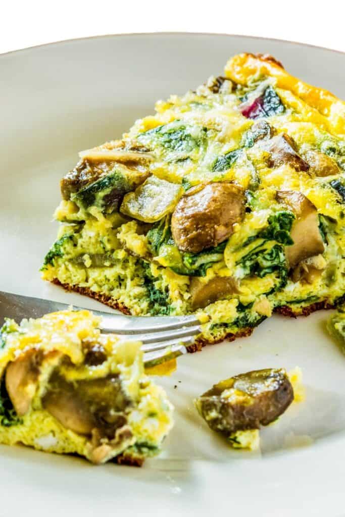 a wedge of Spinach Mushroom Frittata cut with a frok
