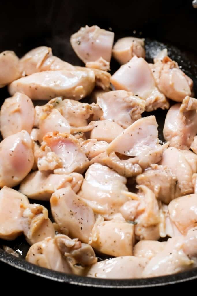 chicken pieces cooking in a pan with olive oil