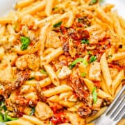 a white plate with Chicken Sundried Tomato Pasta and a fork.