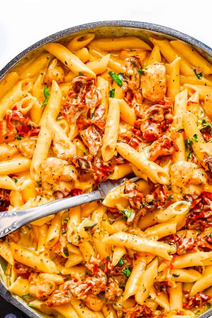 a pot of creamy Sun-Dried Tomato Pasta with chunks of chicken and sundried tomatoes.