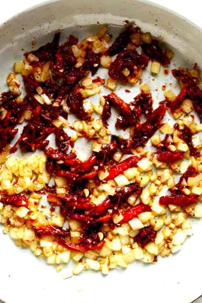 onions and Sun Dried Tomatoes cooking in a pan