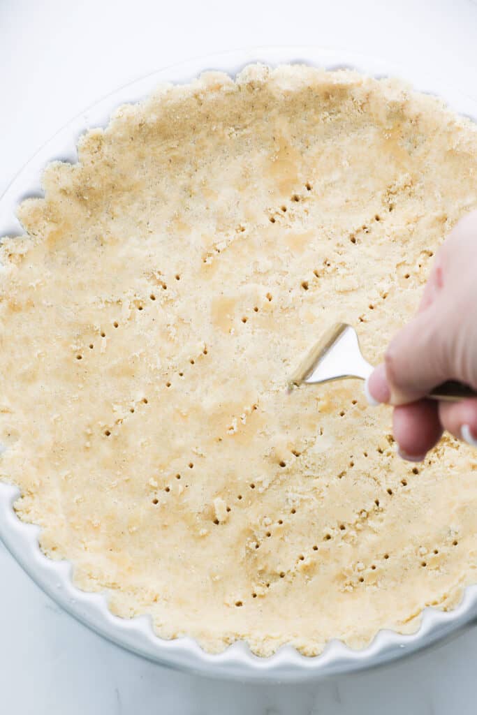 a fork pressing into the dough lined pan