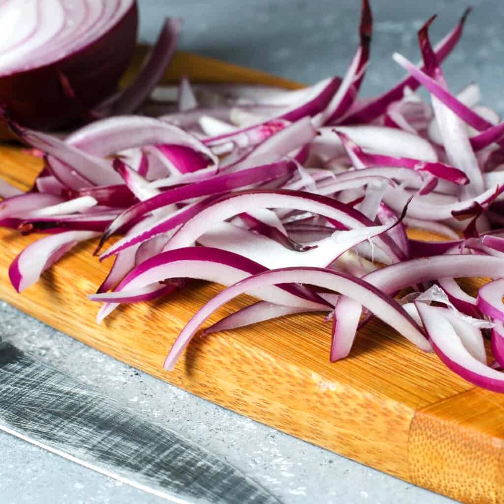 cebollas rojas cortadas en una tabla para cortar