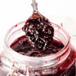 a spoon with cherry ham over the full jar