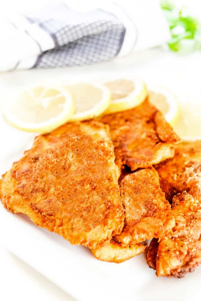 a plate of Crispy Pan Fried Fish with lemons in the background