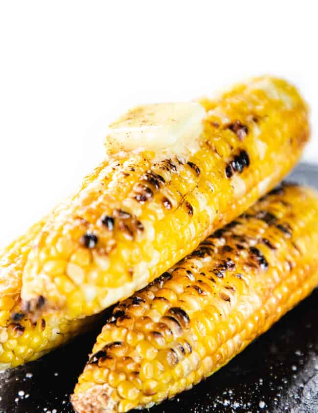 Three ears of Grilled Corn On The Cob topped with a pad of butter