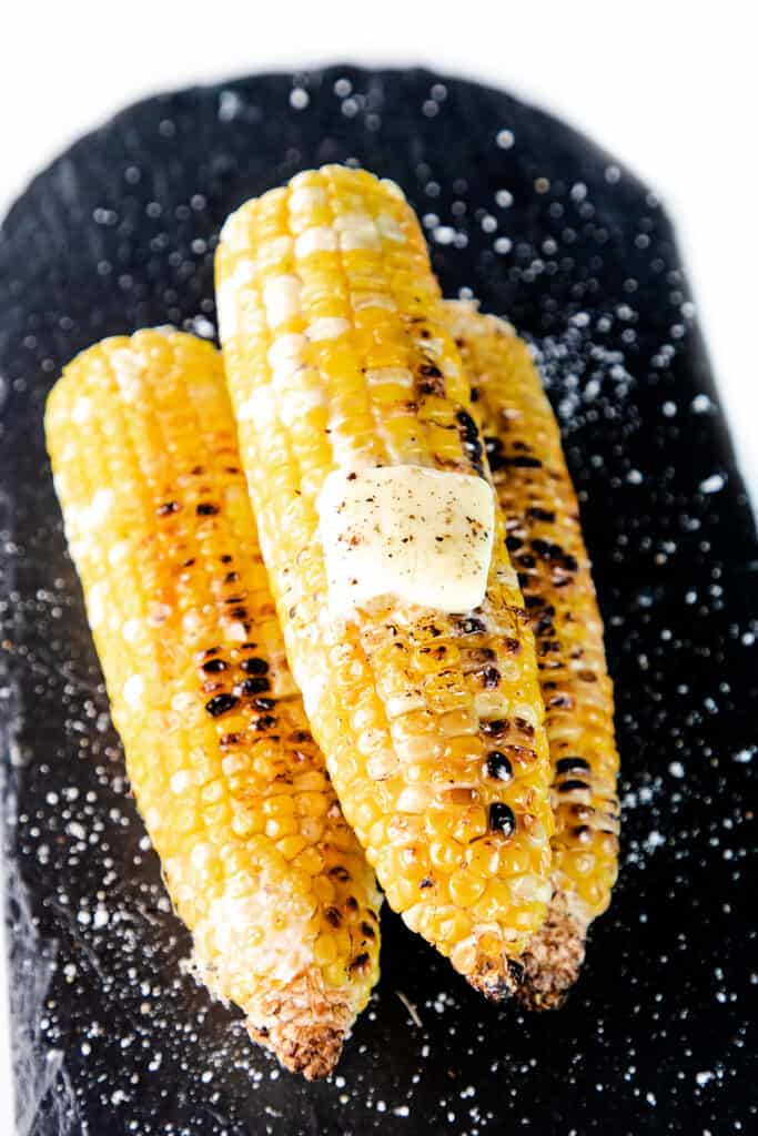 three ears of grilled corn on a black plate